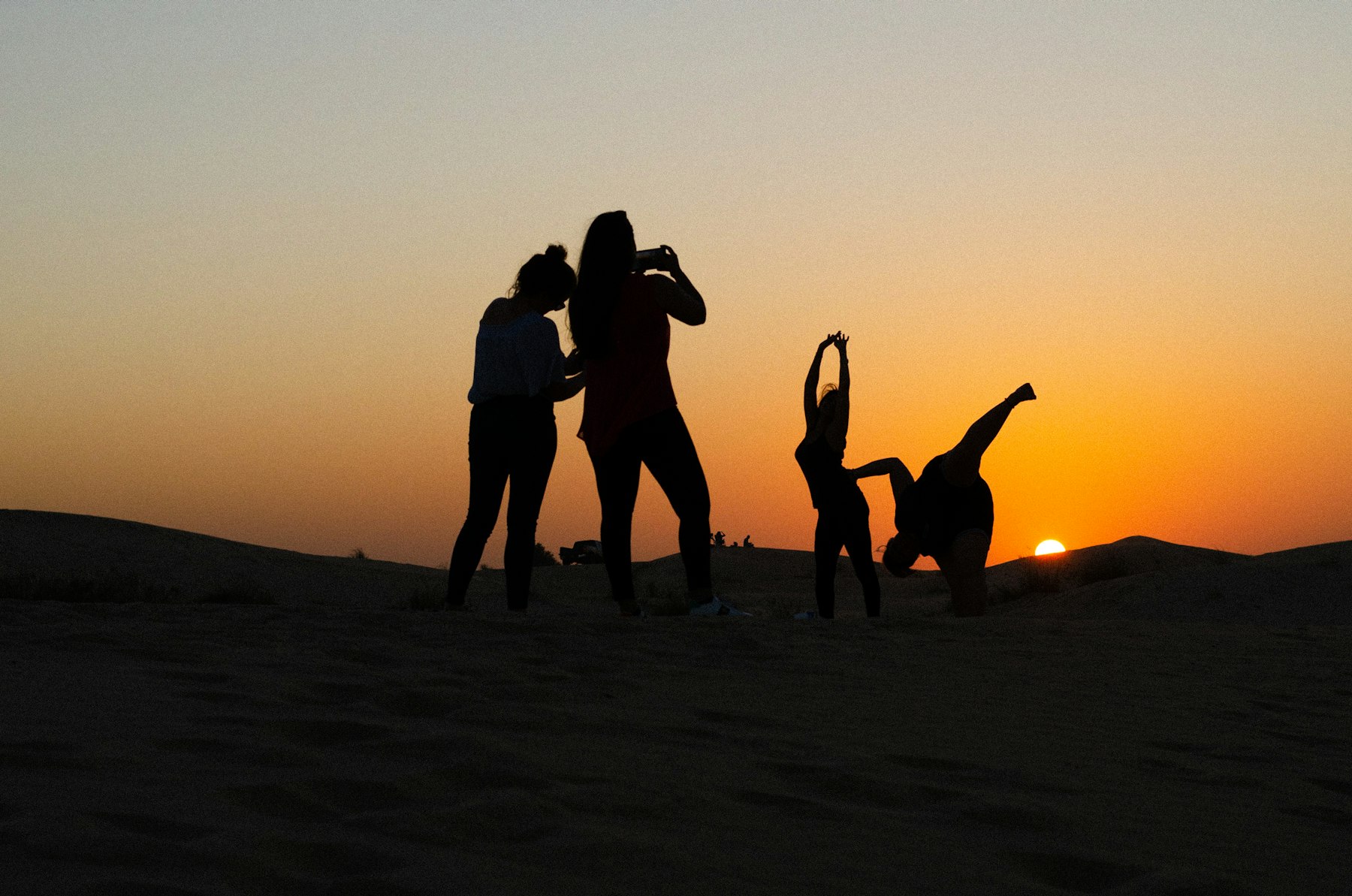 Groupe d'amis face au coucher du soleil dans le désert
